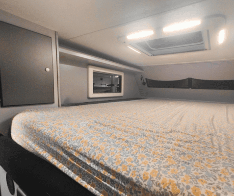 A bed with a yellow and white bedspread.