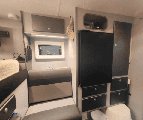 A black refrigerator and some white appliances in a room.