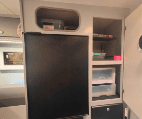 A black refrigerator in the middle of a kitchen.