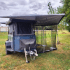 A small trailer with an awning and tent attached.