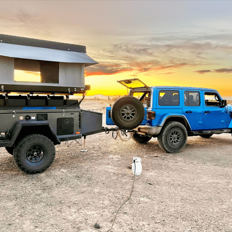 Blue Jeep with camper at sunset.