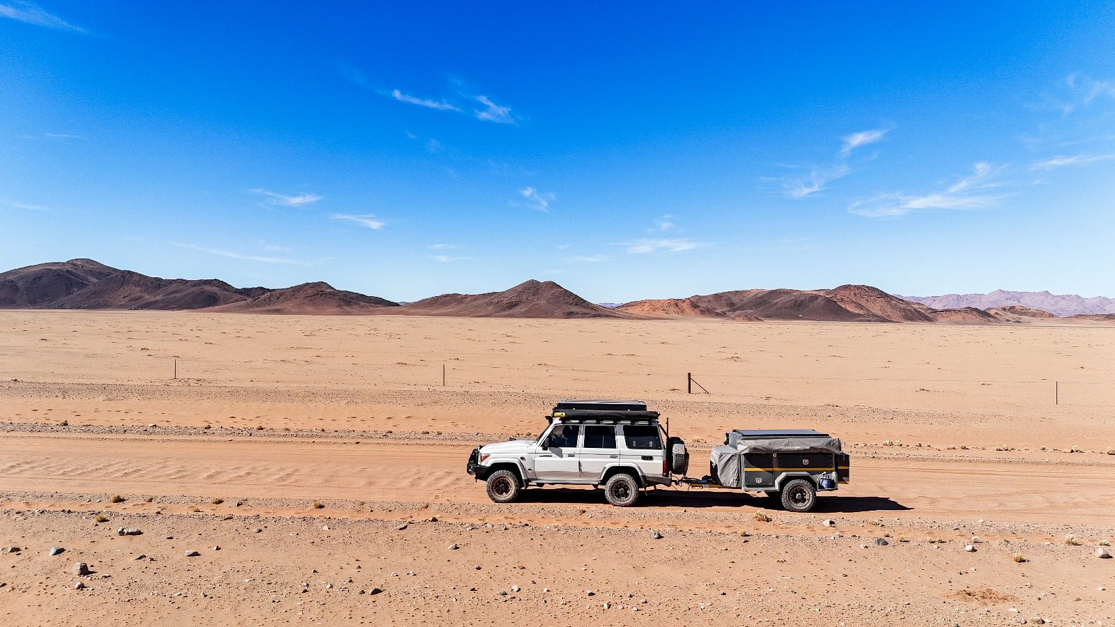 Off-road vehicle towing trailer in desert.