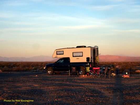 Truck camper parked in desert landscape.