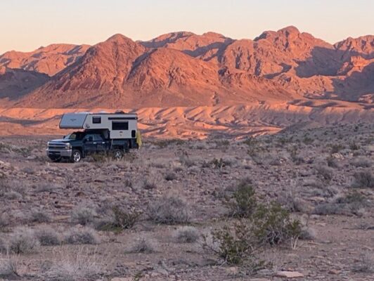 Camper in desert landscape with mountains background.