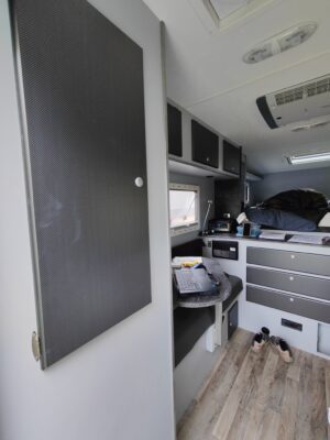 Camper interior with bed and storage cabinets.
