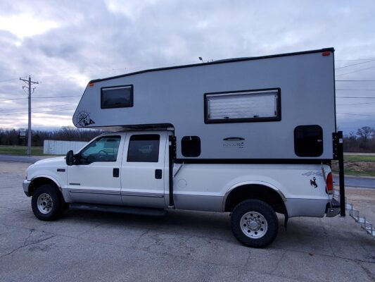 White truck with large camper attachment.