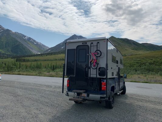 Camper truck with bike in mountain setting.