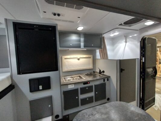 Compact camper kitchen with stove and sink.