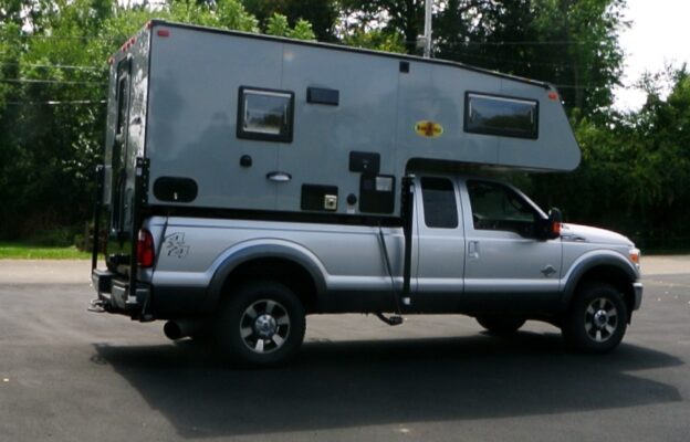 Truck with a camper on paved road.