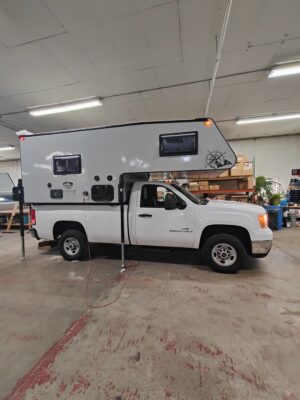 White truck with camper in a garage.