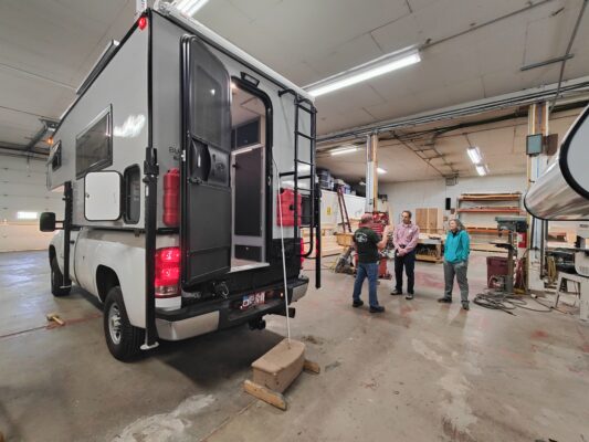 Camper van in garage with three people.