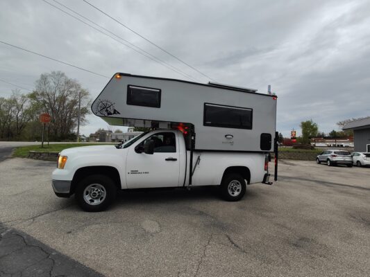 White truck with a camper attachment.