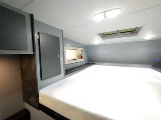 Modern RV interior with bed and cabinets.